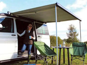Thule 6300 Anthracite Roof Mount Awning Mystic Grey - 3.25m attached to a van with a woman enjoying outdoor leisure.
