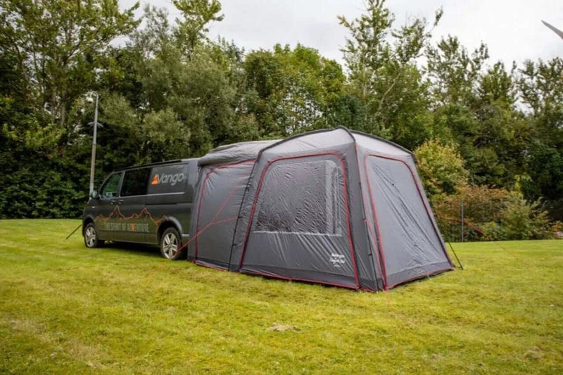 Vango Tailgate Pole Drive Away Awning - Low attached to a vehicle in a green field, showcasing its design and functionality.